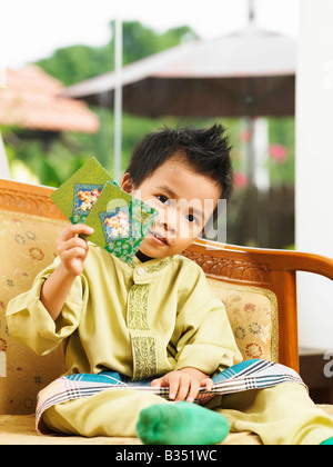 Ragazzo malese che mostra due pacchetto verde Foto Stock