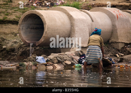 Un dhobi lava i panni nel fiume Gange a Varanasi (India). Foto Stock