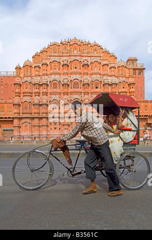 Un ampio angolo di visione della facciata del Hawa Mahal (palazzo dei venti) con un risciò ciclo essendo spinto in passato. Foto Stock