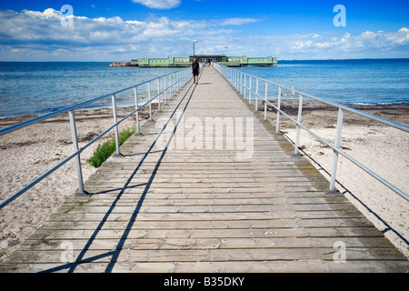 Un lungo molo in legno collega Ribersborg beach a Malmö, in Svezia con il vecchio open-air nuoto vasca da bagno noto come Kallbadhuset. Foto Stock