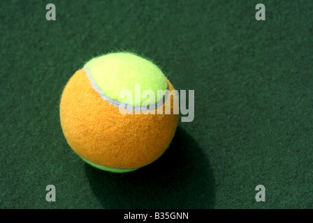 Ombra giallo/arancione palla da tennis isolato sul verde campo da tennis Foto Stock