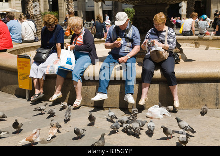 Spagna Barcellona quattro turisti maturo sedersi sulla fontana in Placa Reial e mangiare con piccioni nelle vicinanze piazza neoclassica plaza Foto Stock