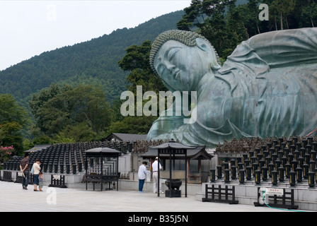 Adoratori di pregare prima di un gigante Buddha reclinato statua al tempio Nanzoin a Fukuoka Foto Stock