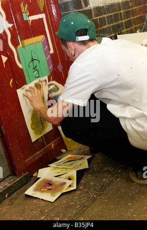 L'artista di strada con stencil e vernice spray a Banksy 2008 del festival lattine in London's Leake Street Foto Stock