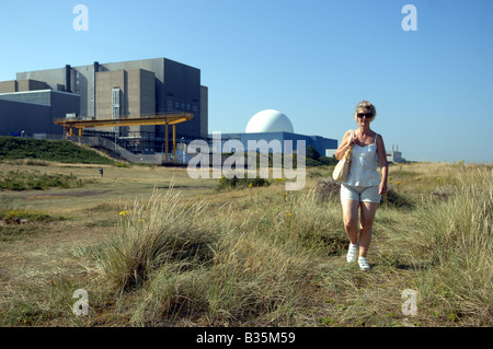 Una donna passa accanto alla centrale nucleare di Sizewell Sulla costa di Suffolk Foto Stock