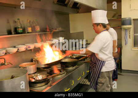 Maschio Chef tailandese per la cottura con il wok fiammeggianti in un ristorante di cucina, cucina Orientale Foto Stock