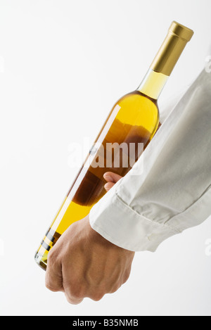 Uomo che mostra una bottiglia di vino bianco, vista ritagliata Foto Stock