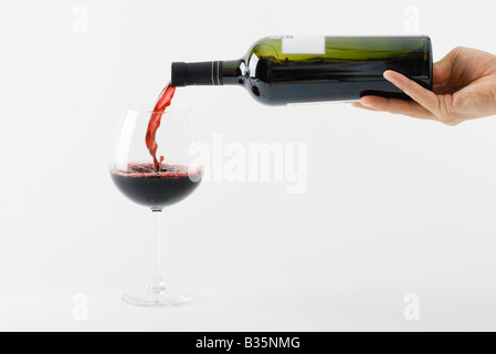 Mano versando il vino rosso in vetro Foto Stock