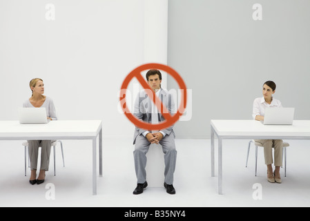Due donne seduti davanti al computer laptop, un cartello di segnalazione sull uomo accigliata tra di essi Foto Stock