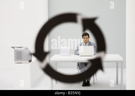 Professional uomo seduto in ufficio, guardando la telecamera attraverso il simbolo di freccia in primo piano Foto Stock