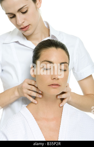 Terapista del massaggio dando donna massaggio collo a occhi chiusi Foto Stock
