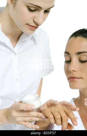 Estetista di applicare una crema idratante per la donna la mano Foto Stock