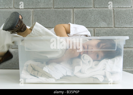Little Boy giacente in contenitore in plastica sulla parte superiore del servizio lavanderia Foto Stock