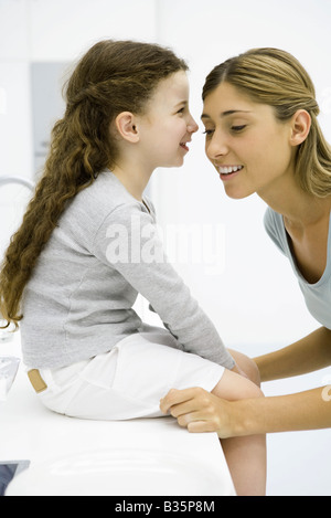 Bambina whispering in sua madre orecchio, vista laterale Foto Stock