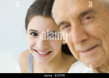 Teen girl cerca su nonno spalla, entrambi sorridenti, concentrarsi sullo sfondo Foto Stock