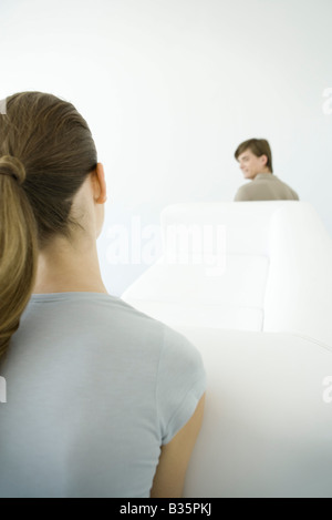 Giovane spostando divano insieme, al di sopra della spalla Foto Stock