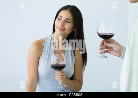 Donna che mantiene un bicchiere di vino e guardando lontano, uomo in piedi nelle vicinanze, vista ritagliata Foto Stock