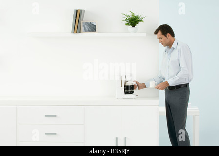 Uomo in piedi dal contatore, il caffè, vista laterale Foto Stock