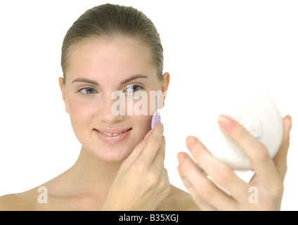 Giovane donna faccia l'applicazione di polvere e sorridente Foto Stock
