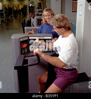 Femmina di personal trainer lavora con il suo cliente su una pressa da banco in un club di salute Foto Stock