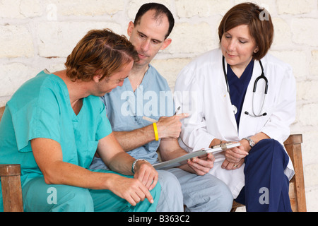 Tre infermieri seduta su una panchina discutendo della carta di lavoro Foto Stock