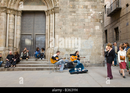 Spagna Barcellona due giovani uomini adulti giocare la chitarra acustica in plaza con open guitar caso la vendita di CD di musica di persone ascoltano Foto Stock