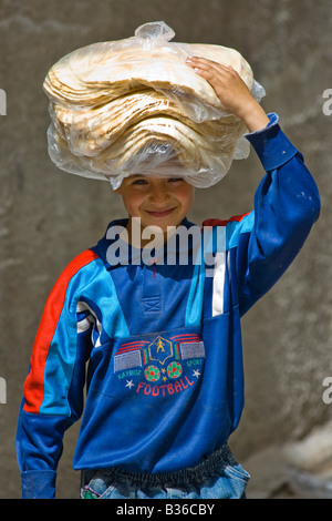 Ragazzo siriano Carring pane fresco sulla sua testa nella città vecchia di Aleppo Siria Foto Stock