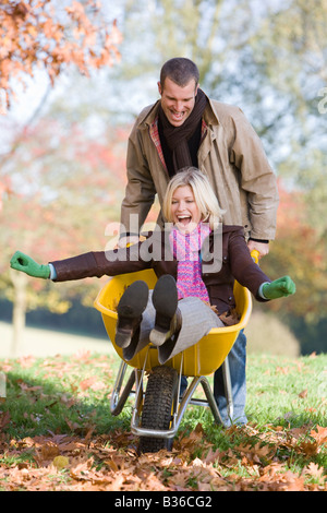 L'uomo all'aperto spingendo la donna in carriola e sorridente (messa a fuoco selettiva) Foto Stock