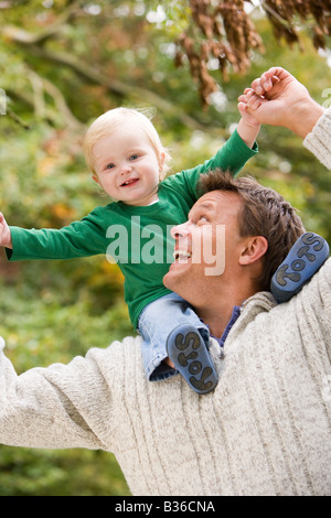 Padre dando baby figlio piggyback Foto Stock