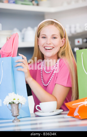 Giovane donna seduta al tavolo per una pausa dallo shopping Foto Stock