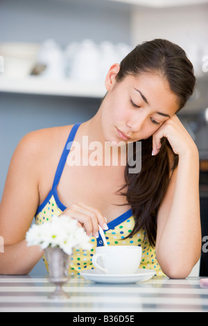 Giovane donna seduti ad un tavolo a bere un tè Foto Stock