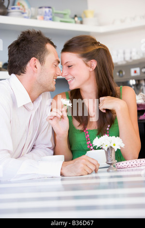 Coppia giovane seduti ad un tavolo che ognuno guarda negli occhi dell'altro Foto Stock