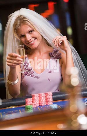 Donna in velo nuziale nel casinò giocare alla roulette e sorridente (messa a fuoco selettiva) Foto Stock