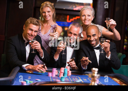 Cinque persone in casinò giocare alla roulette e sorridente (messa a fuoco selettiva) Foto Stock