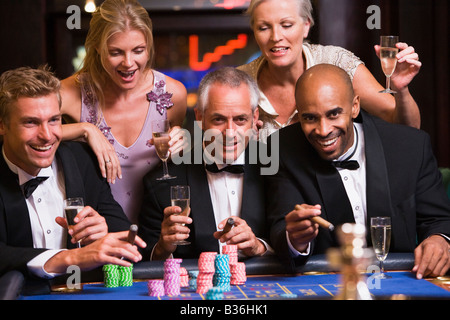 Cinque persone in casinò giocare alla roulette e sorridente (messa a fuoco selettiva) Foto Stock