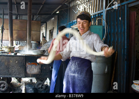 Uyghur uomo rendendo Laghman freschi Tagliatelle al mercato domenicale di Kashgar nella provincia dello Xinjiang in Cina Foto Stock