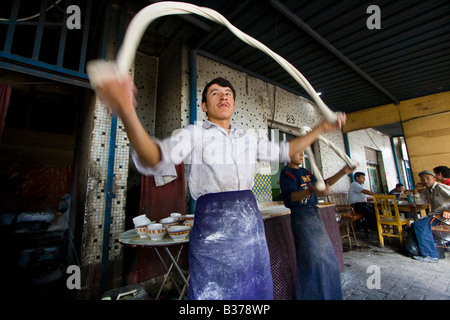 Uyghur uomo rendendo Laghman freschi Tagliatelle al mercato domenicale di Kashgar nella provincia dello Xinjiang in Cina Foto Stock