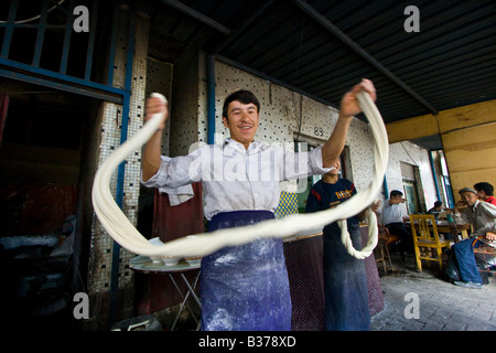 Uyghur uomo rendendo Laghman freschi Tagliatelle al mercato domenicale di Kashgar nella provincia dello Xinjiang in Cina Foto Stock