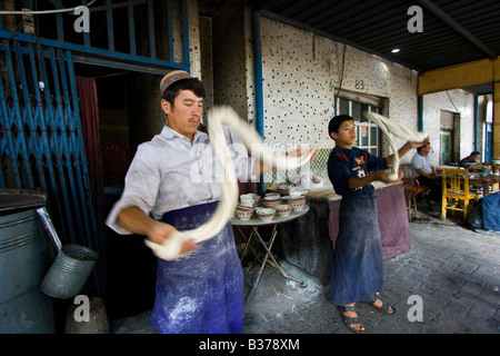 Uyghur uomo rendendo Laghman freschi Tagliatelle al mercato domenicale di Kashgar nella provincia dello Xinjiang in Cina Foto Stock