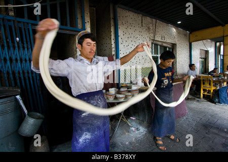 Uyghur uomo rendendo Laghman freschi Tagliatelle al mercato domenicale di Kashgar nella provincia dello Xinjiang in Cina Foto Stock