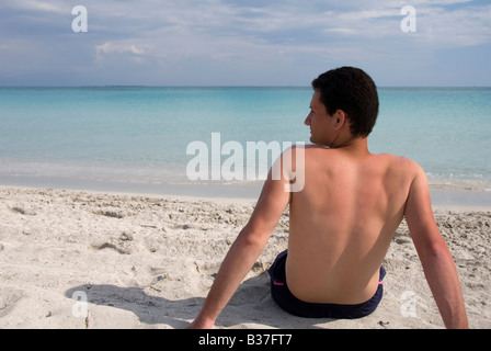 Un uomo seduto sulla spiaggia Foto Stock