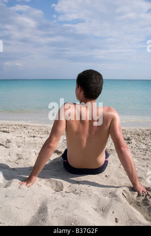 Un uomo seduto sulla spiaggia Foto Stock