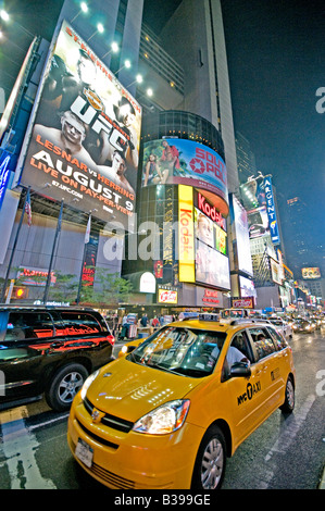 Times Square Night Scene Yellow taxi New York City // NEW YORK CITY, NY - Una vivace scena notturna di Times Square, l'iconico incrocio di Midtown Manhattan, brulica di attività. I taxi gialli navigano attraverso le strade affollate, il loro colore distintivo si distingue sullo sfondo di luminosi cartelli al neon, enormi cartelloni e schermi LED. Un gran numero di pedoni, sia turisti che locali, riempiono i marciapiedi e i marciapiedi, incarnando l'energia della "città che non dorme mai". Foto Stock