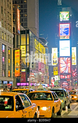 Times Square Neon Signals e Yellow Taxis New York City // NEW YORK CITY, New York - Una vivace scena notturna di Times Square, l'iconico incrocio di Midtown Manhattan, brulica di attività. I taxi gialli navigano attraverso le strade affollate, il loro colore distintivo si distingue sullo sfondo di luminosi cartelli al neon, enormi cartelloni e schermi LED. Un gran numero di pedoni, sia turisti che locali, riempiono i marciapiedi e i marciapiedi, incarnando l'energia della "città che non dorme mai". Foto Stock