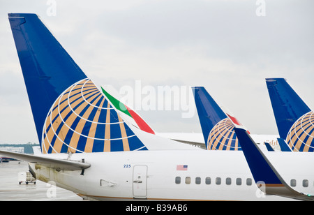 United Airlines Jet at Gate Houston Texas | HOUSTON, Texas, Stati Uniti - le pinne di coda con il logo blu e oro di United Airlines si allineano all'aeroporto intercontinentale George Bush, con una coda livrea continentale visibile dietro di loro. Il marchio del globo risale alla fusione di United nel 2010 con Continental Airlines, che ha reso IAH uno dei cinque hub nazionali di United. L'aereo '225' porta una piccola bandiera statunitense vicino alla sua porta anteriore, standard sulla maggior parte dei jet commerciali registrati negli Stati Uniti. Foto Stock