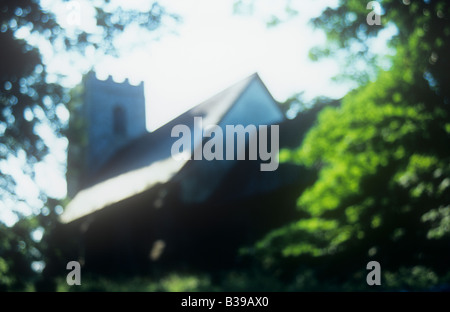 Vista impressioniste di archetipo della chiesa inglese con torre campanaria circondata da foglie di acero retroilluminato e faggi Foto Stock