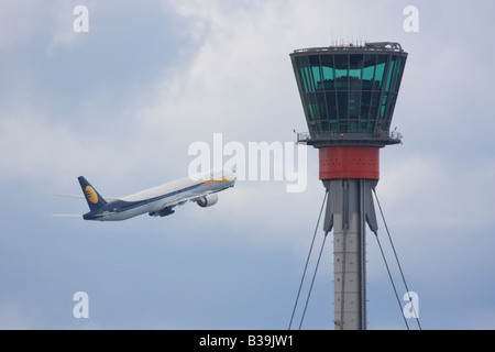 Jet Airways Boeing 777-35R/ER di decollare in background di Londra Heathrow torre di controllo. Foto Stock