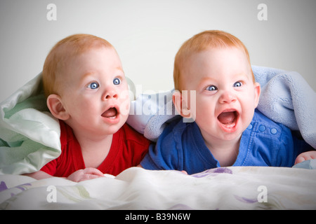 Giovane e bella baby twin ragazzi con i capelli rossi che giace sulla parte anteriore sotto la coperta morbida Foto Stock