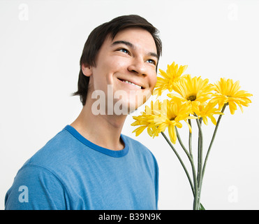Asian giovane azienda bouquet di giallo margherite gerber sorridente Foto Stock