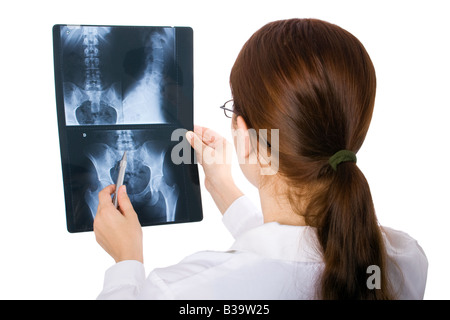 Medico donna esaminando un bacino x-ray su sfondo bianco. /// Donna esame pelvico cercando x ray tagliato fuori per colonna vertebrale di esclusione di hips femore backbone spinale Foto Stock